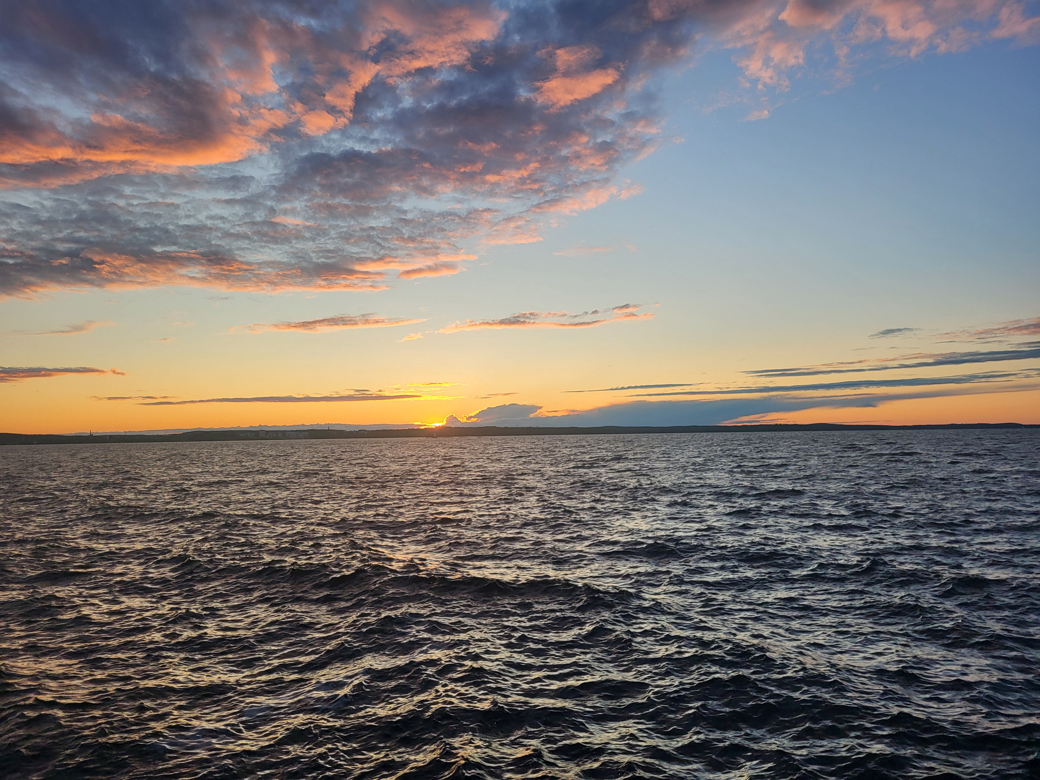 Gouden zonsondergang met de zon net onder de horizon boven open Fins water, warm en groots